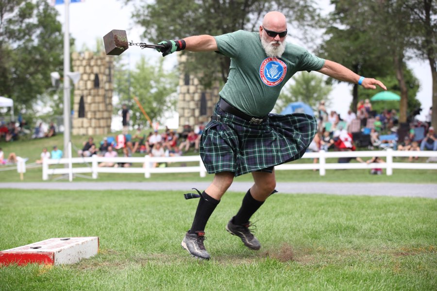 man in kilt swinging a heavy cube.