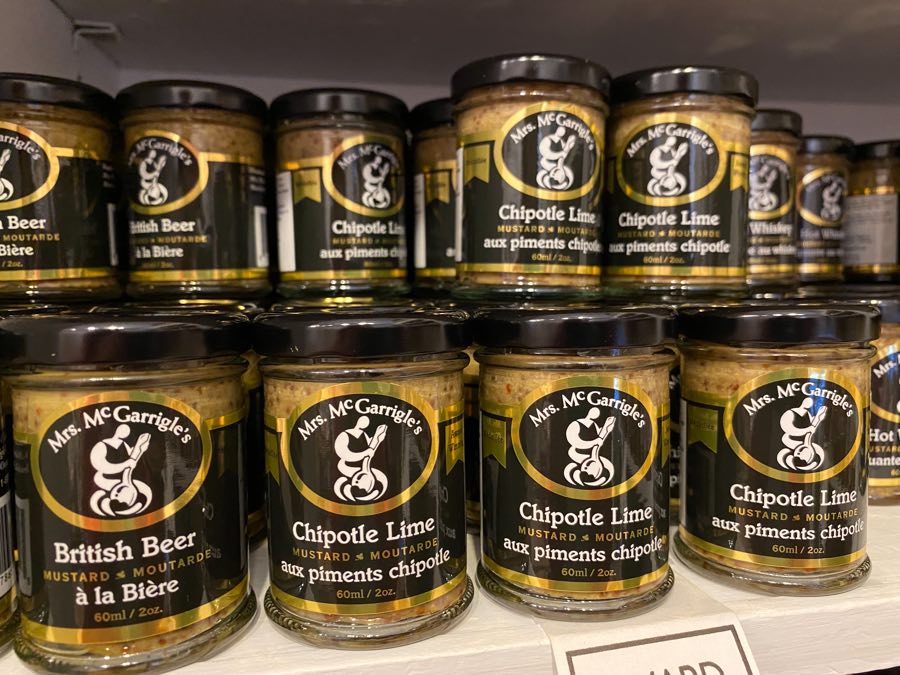 a shelf with small jars of chipotle lime and british beer mustard.