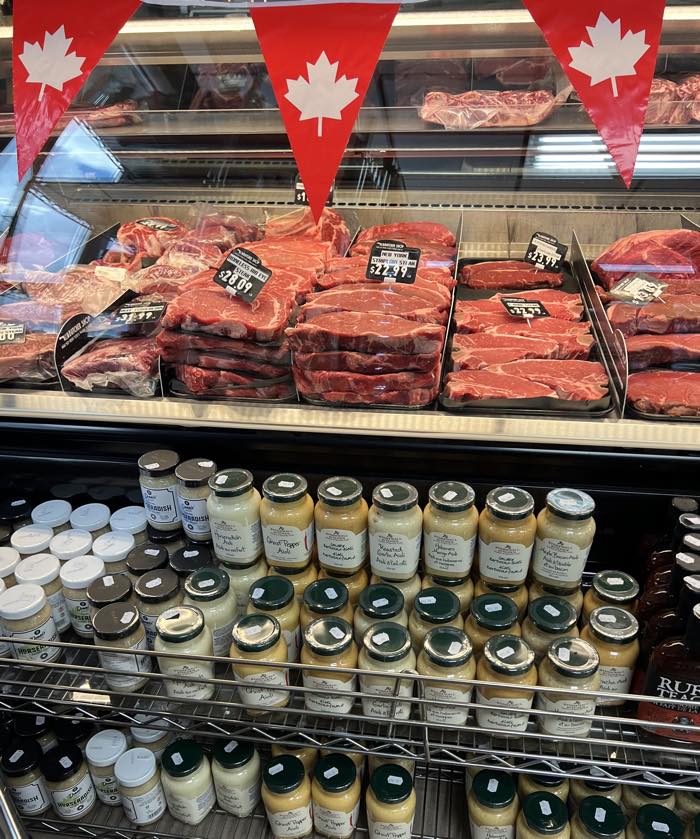 steaks in a refrigerated display case behind a shelf of mustards