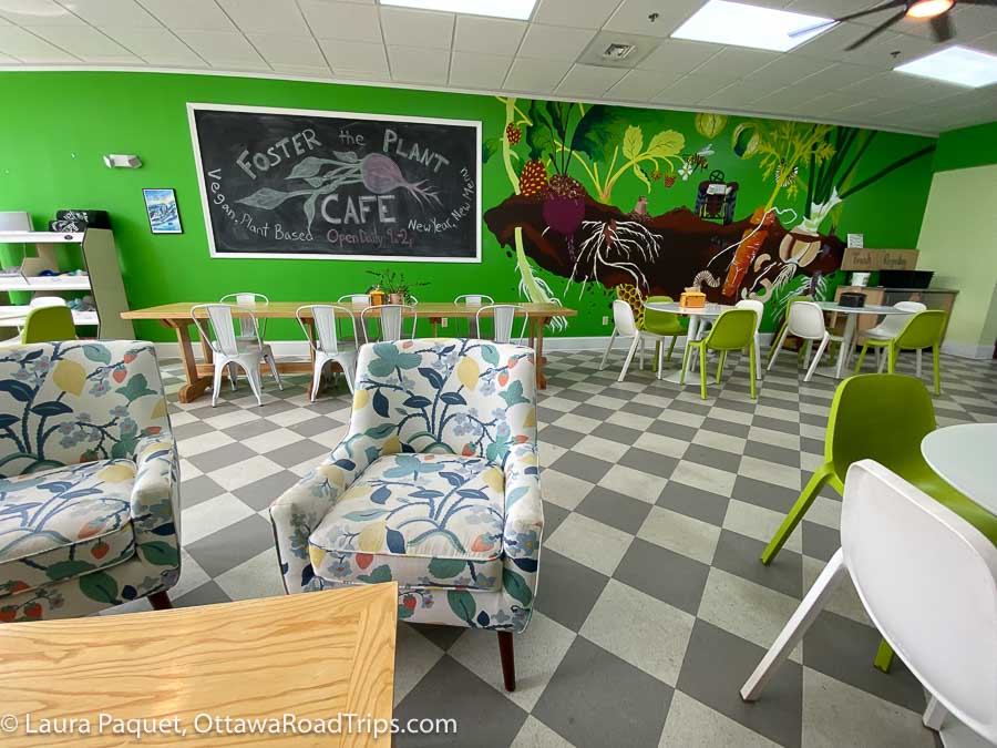bright green mural, flowered chairs and checkerboard floor inside foster the plant, one of the only vegan cafes in st. lawrence county, new york.
