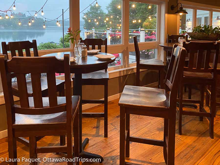 wooden table and chairs near big windows overlooking a lake at jake's on the Water in St Lawrence County New York.
