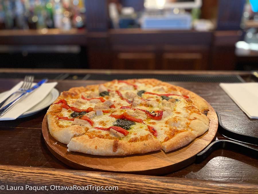 a personal-sized thin crust pizza on a wooden serving board at jake's on the Water near Potsdam, New York.