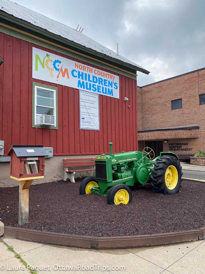 a small green-and-yellow john deere tractor outside the north country children's Museum in Potsdam, New York.