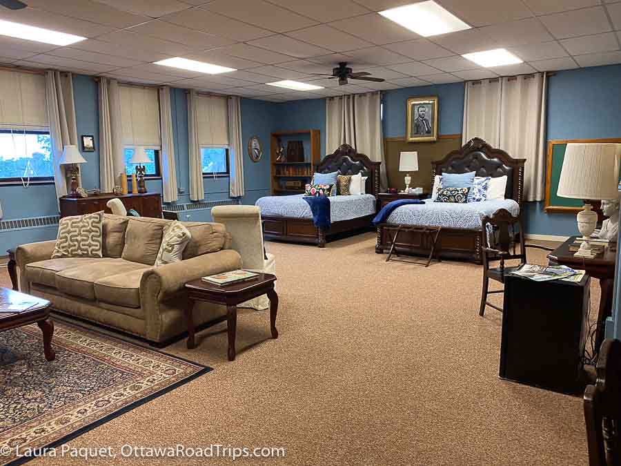 large hotel room with two sleigh beds, couch, chairs and desk at the sherman inn in ogdensburg new york.