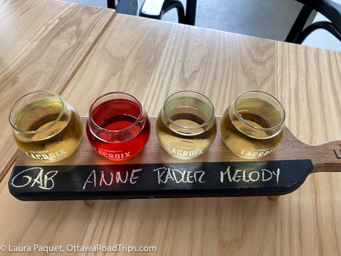 four small glasses of cider in a wooden holder, photographed from above