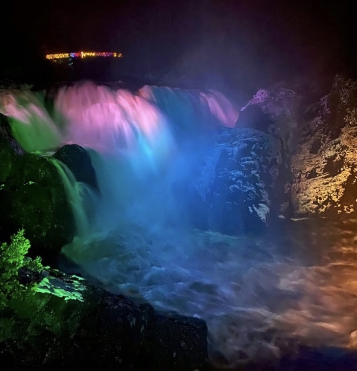 waterfall illuminated with green, pink and blue lights at chutes coulonge park in quebec
