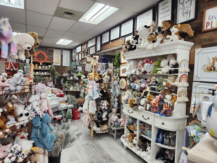 wooden shelves filled with stuffed animals and linens, with decorative plaques on the walls.
