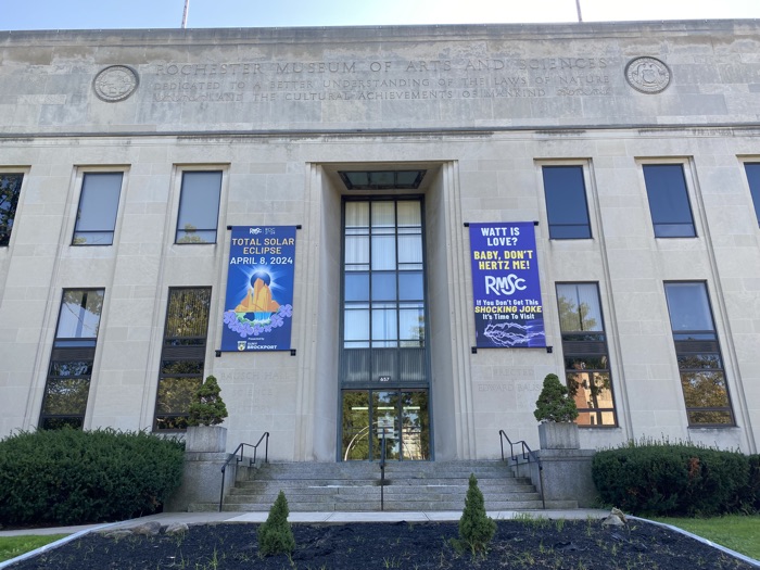 large grey museum banner with a blue banner promoting the 2024 total solar eclipse