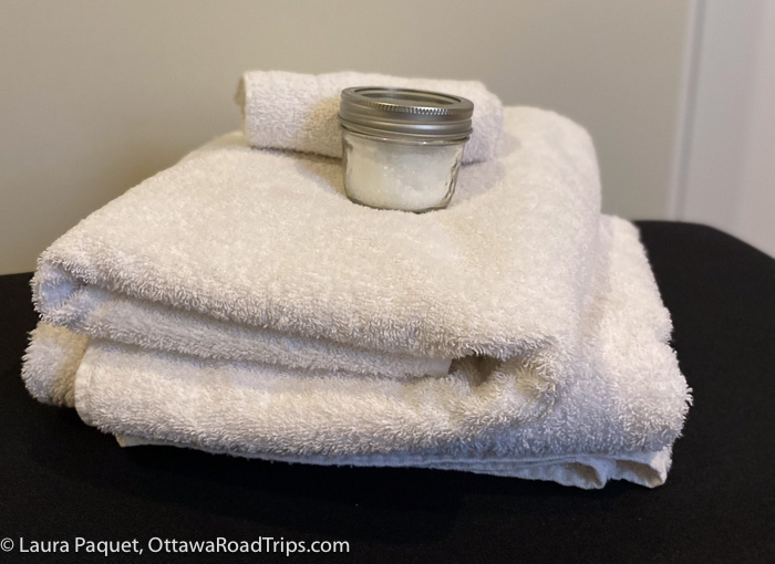 folded white towels with small jar of epsom salts on top