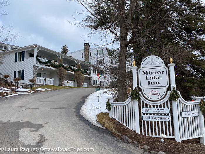entrance drive to the mirror lake inn, a large white wooden building in lake placid