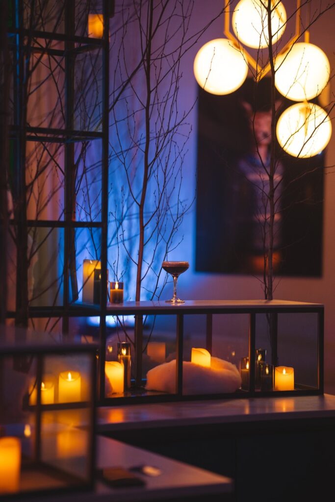Dimly lit hotel lounge with tree branches, a cocktail in a coupe and candles