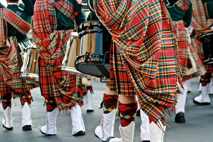 the backs and feet of marching bagpipers dressed in tartans