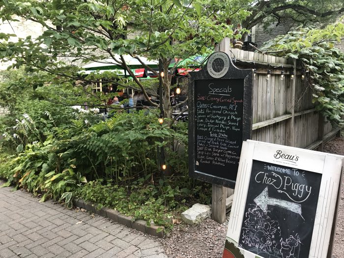 entrance to a leafy patio with specials on a chalkboard at chez piggy in kingston.