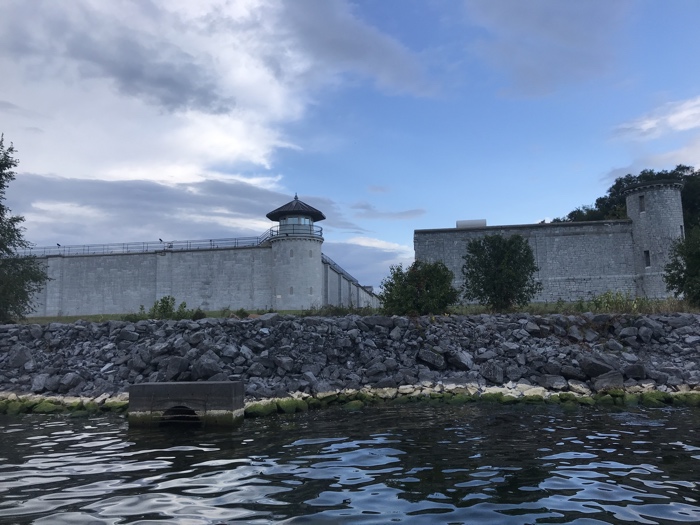 high limestone walls and an observation tower of kingston penitentiary beside lake ontario.