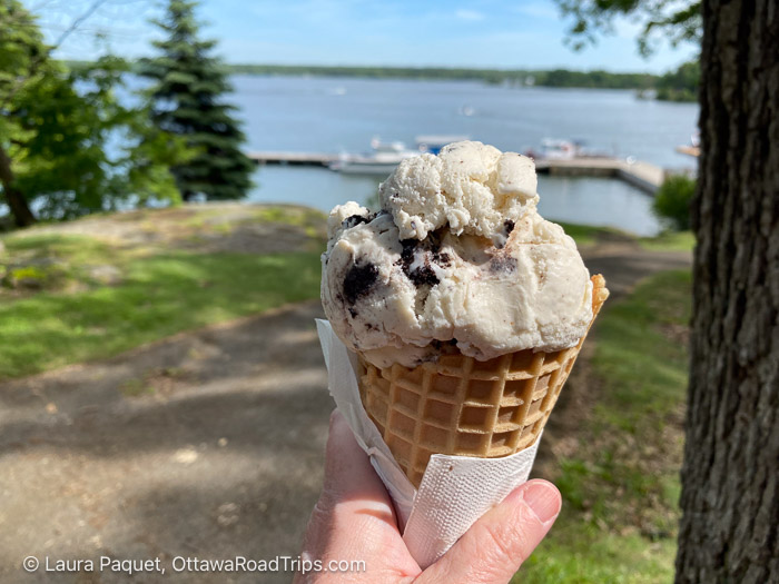 closeup of ice cream in a waffle cone with a dock and river blurred in the background