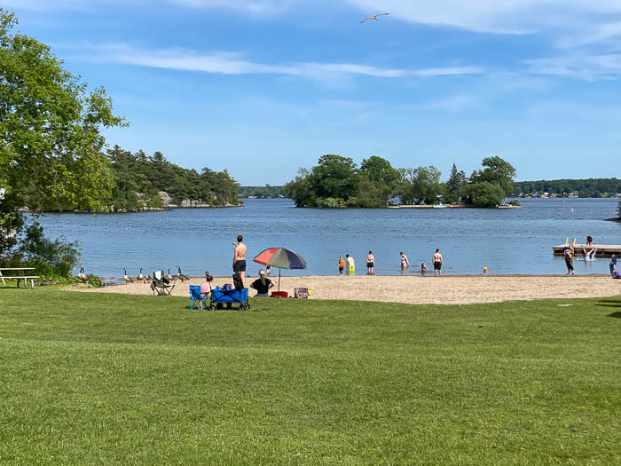 people swimming on one of many beaches near ottawa with small islands in background