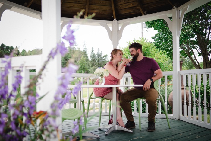 woman and man with intertwined arms drinking wine in a gazebo