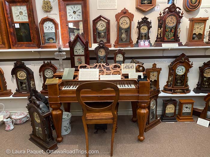 shelves lined with mantel clocks behind a small keyboard instrument at the canadian clock museum in deep river.