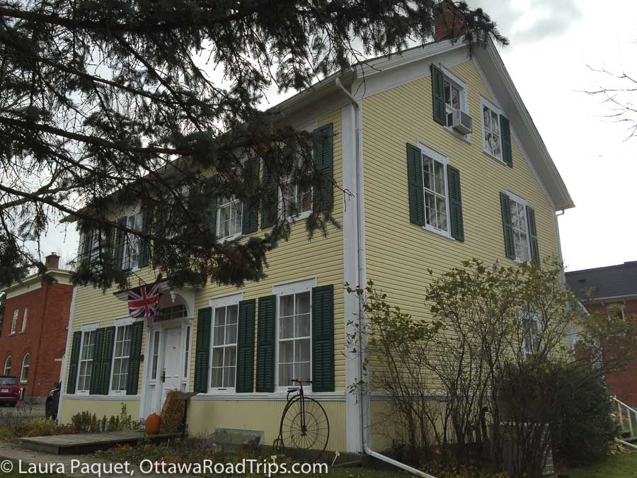 large yellow clapboard house with paned windows and green shutters.