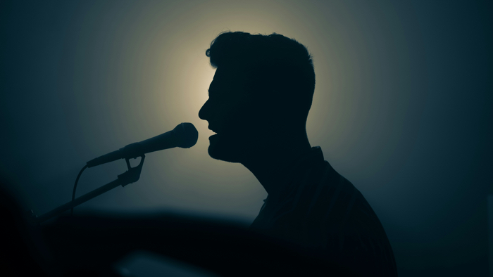 silhouette of a man singing into a microphone