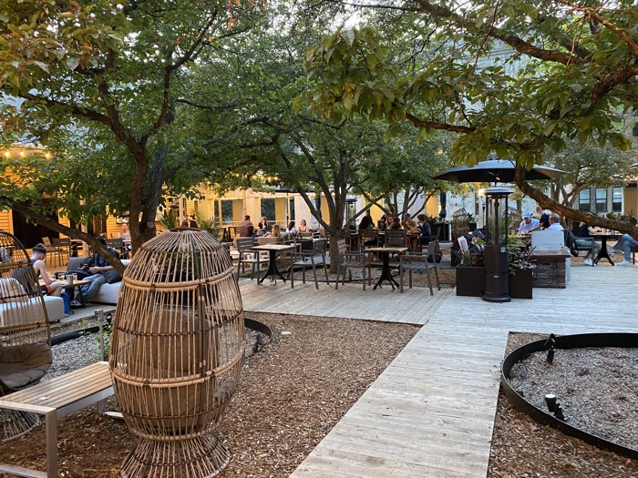 cafe tables and umbrellas on a wooden deck under trees