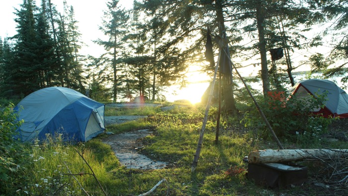 two small round tents beside a lake