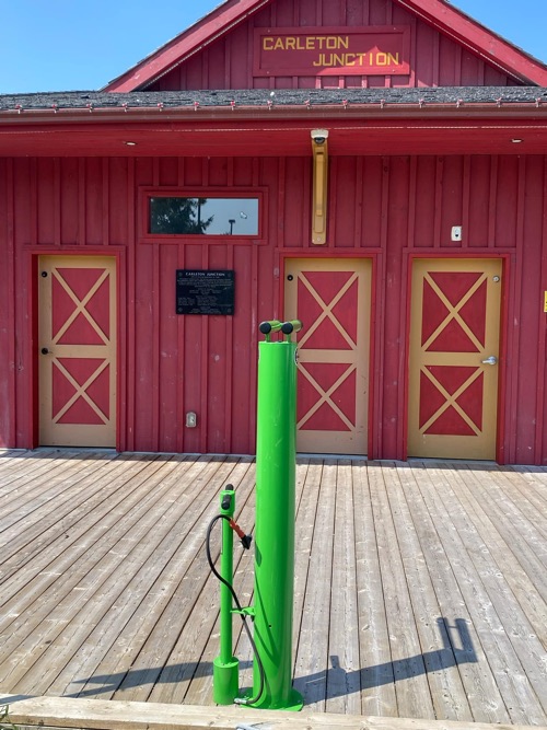 green air pump in front of a red building that looks like a small barn