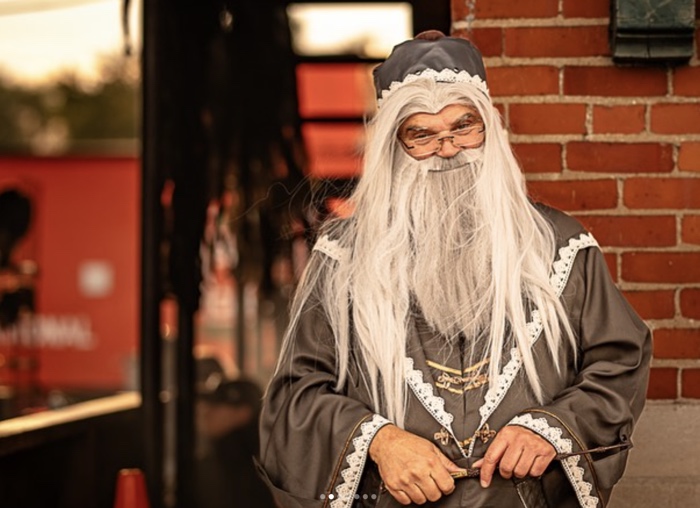 man with long grey hair and beard in grey magical costume for harry potter event at rmeo