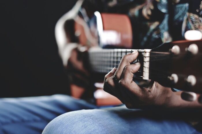ahmed-rizkhaan-guitar-unsplash - Ottawa Road Trips closeup of a hand on a guitar fret with player in background