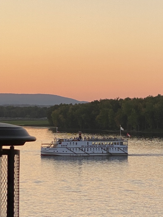 a small white cruise ship on ottawa river at sunset.