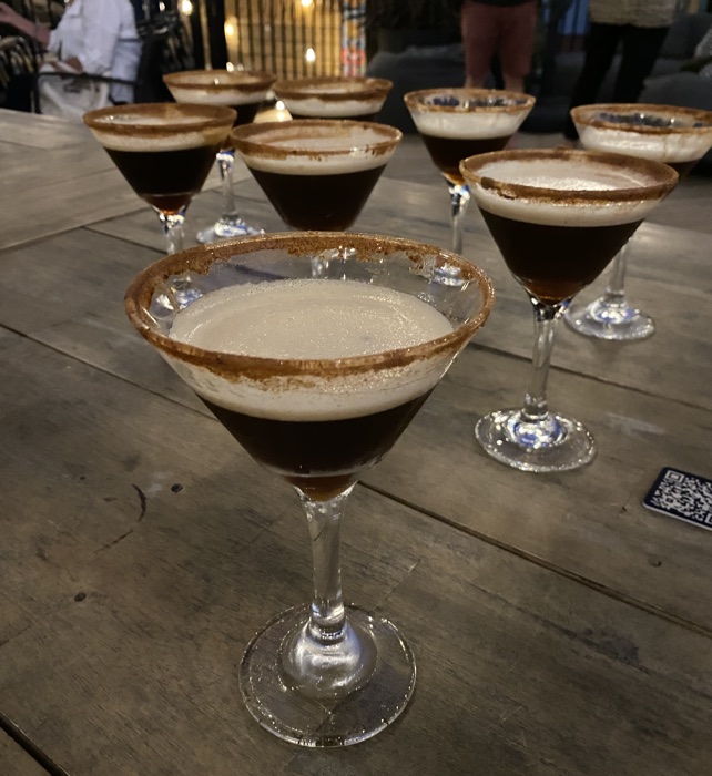 eight salt-rimmed martini glasses on a wooden table