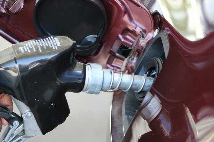 closeup of a gas pump nozzle inserted into a car's gas tank