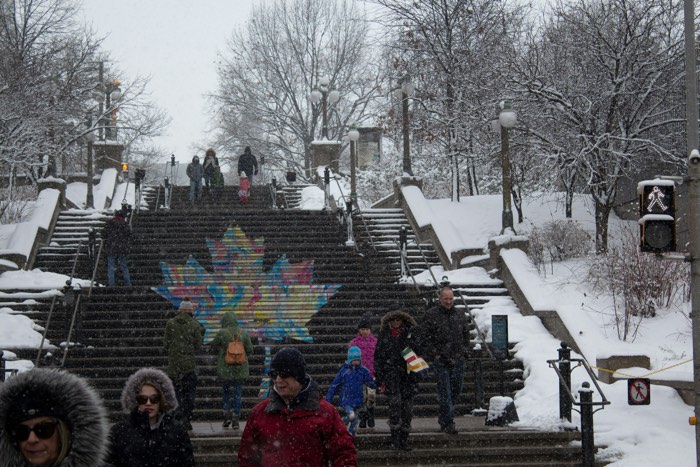 people in winter coats going up and down a big outdoor staircase in a snowstorm