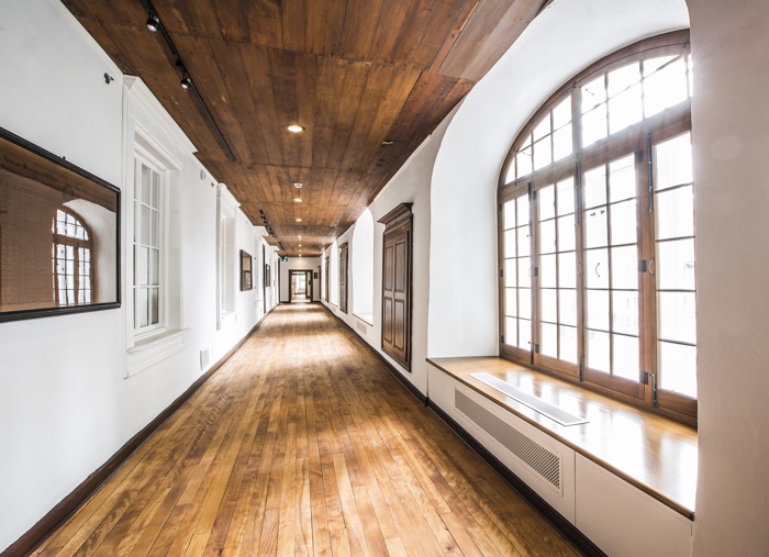 corridor of old building with large arched windows and wood floor and ceiling