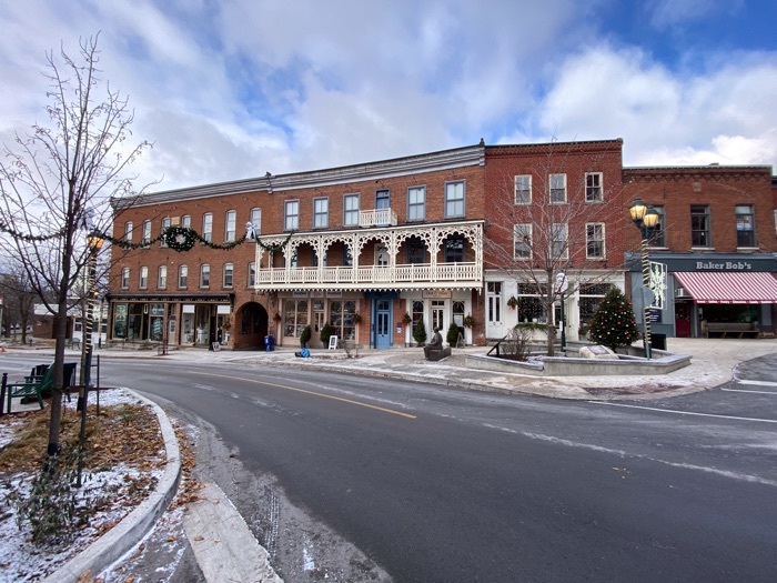 red brick shops on a small street decorated with a wreath, garland and a christmas tree in almonte, ontario.