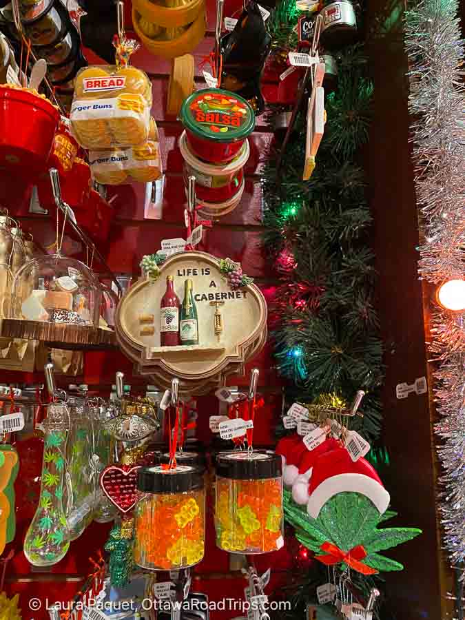 ornaments resembling salsa, wine bottles, hamburger buns, cannabis and other items hanging from hooks on a red wall