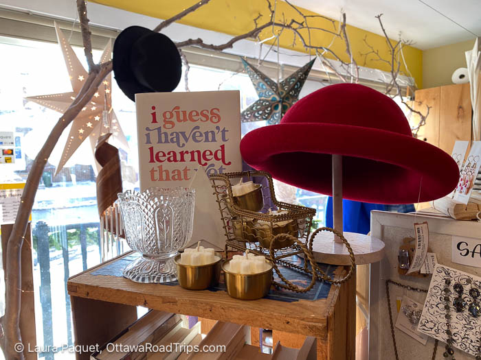 shelf holding a red hat, a book, candles and other items