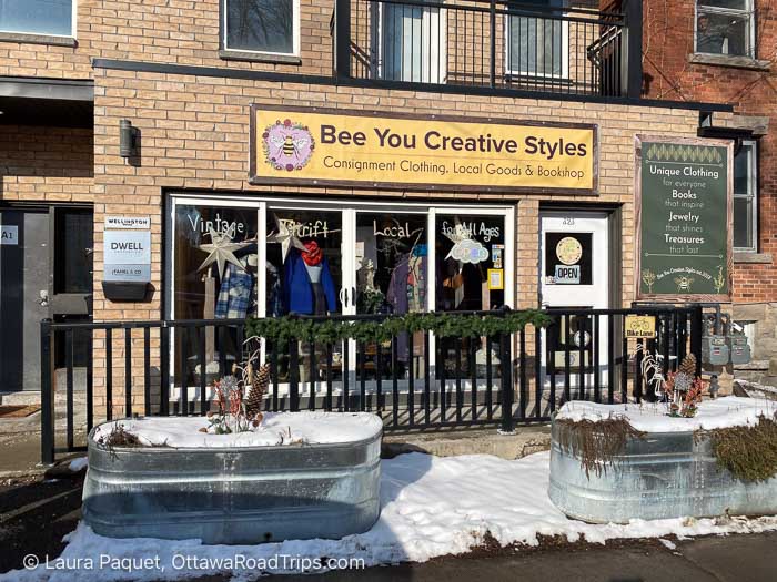 small storefront with window full of clothes and sign reading bee you creative styles