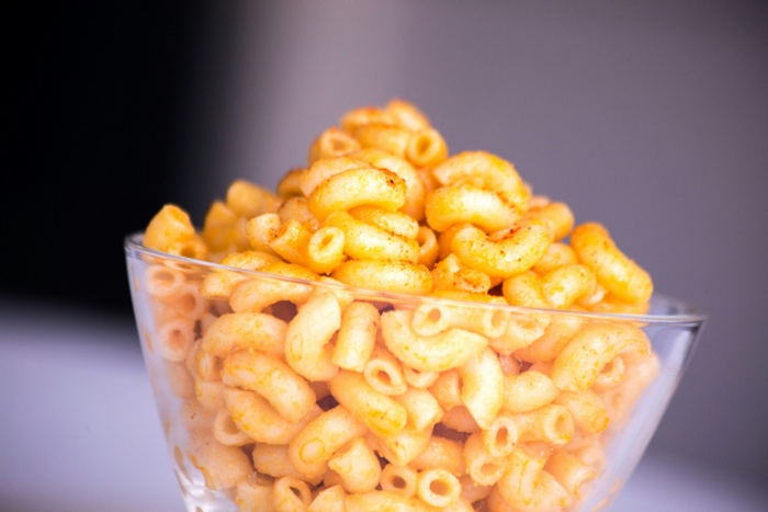 closeup of a glass bowl of macaroni and cheese dusted with paprika