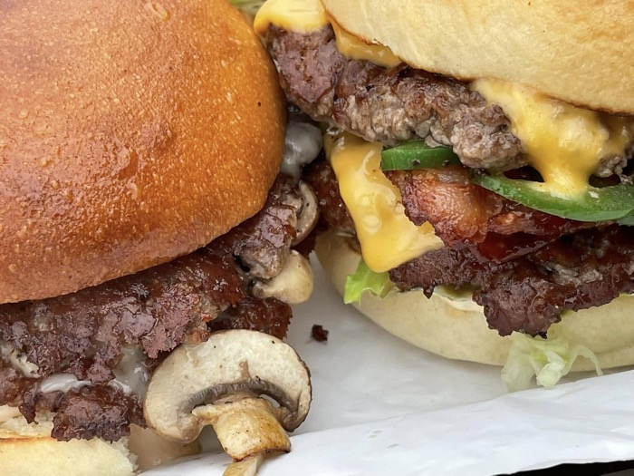 closeup of two double burgers with cheese, bacon and mushrooms