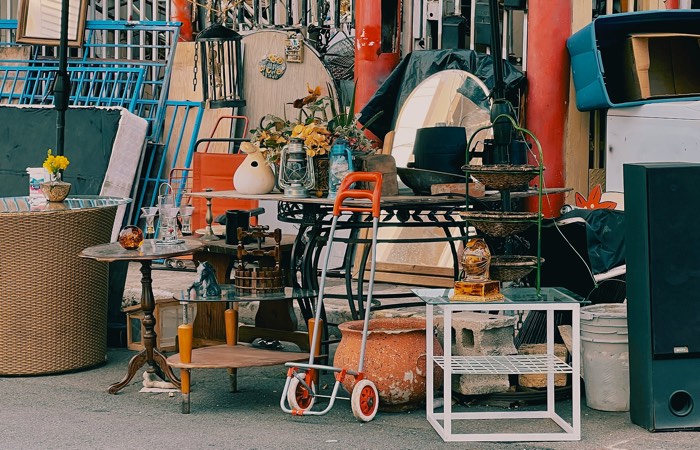 ruoyu-li-garage sale-unsplash - Ottawa Road Trips tables, shelves, glasses, a mirror and other items piled on the pavement for sale.