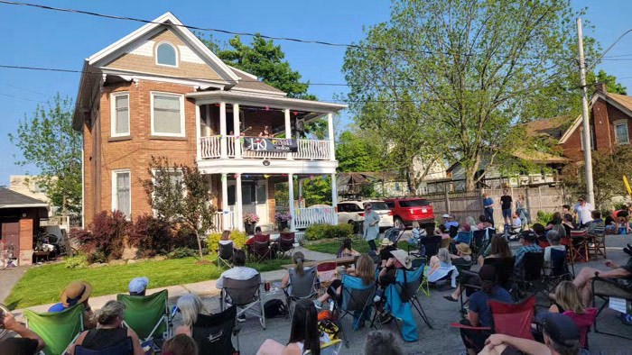 smiths falls porchfest 700 - Ottawa Road Trips people watching musicians on second-floor balcony of a house from folding lawn chairs in the street