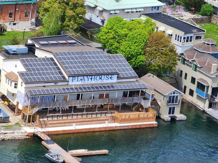 aerial view of a theatre with a long veranda overlooking the water.