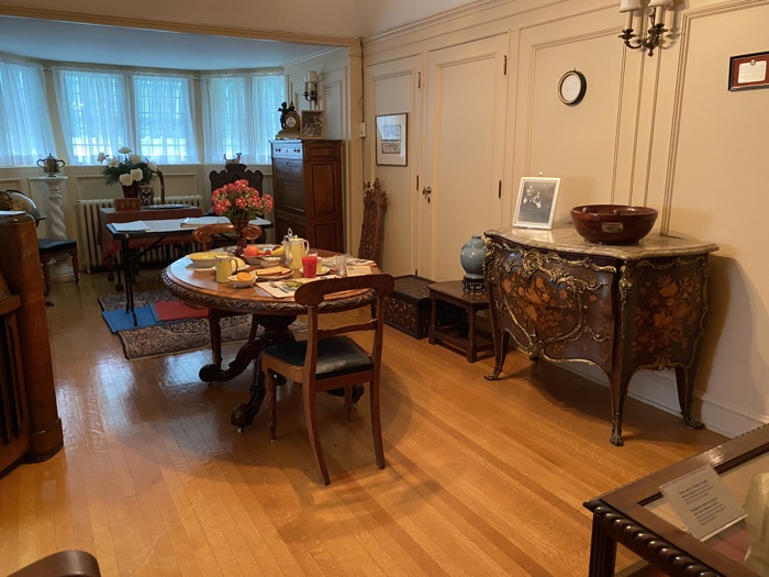 room with round dining table for two set with breakfast for one, and other antiques.