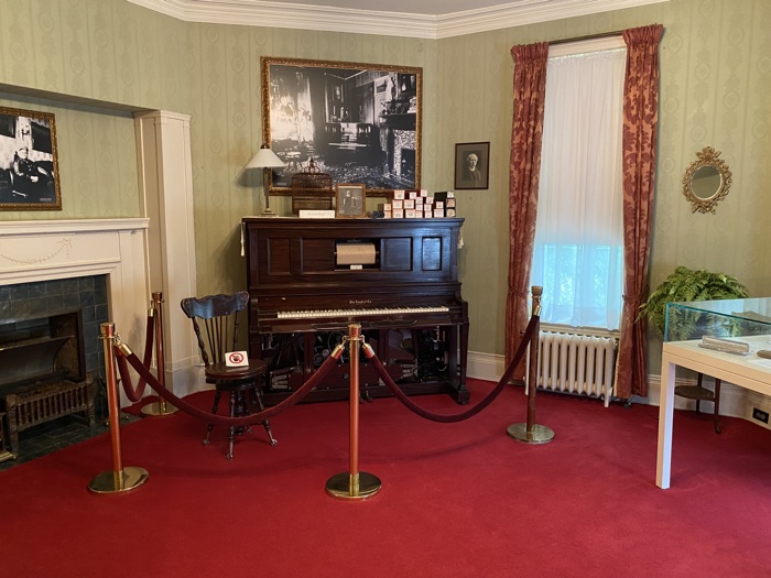 player piano in a room with red carpeting and a green tiled fireplace