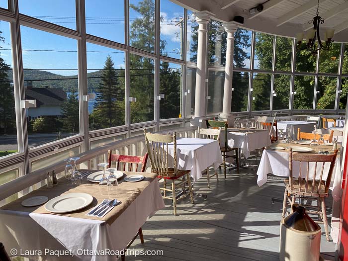 screened porch with small dining tables overlooking a lake