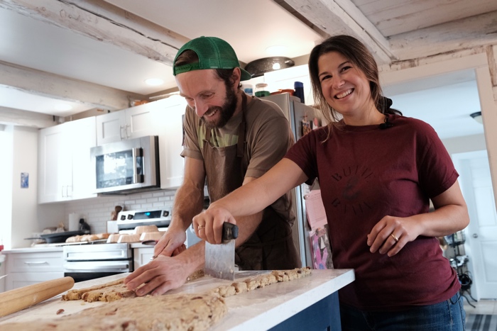 man and woman rolling out and cutting dough in a home kitchen