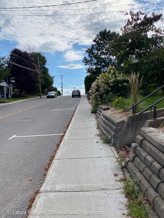road and sidewalk leading up a steep hill, with front yards on each side
