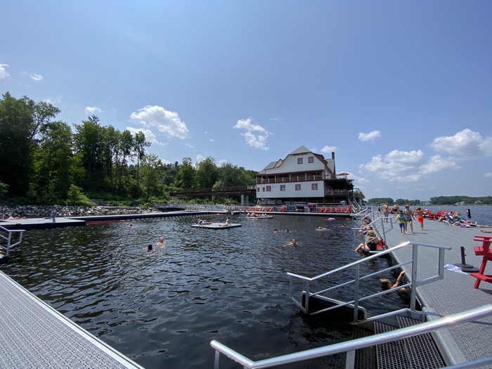 enclosed pool on the ottawa river with swimmers in pool and restored boathouse in background