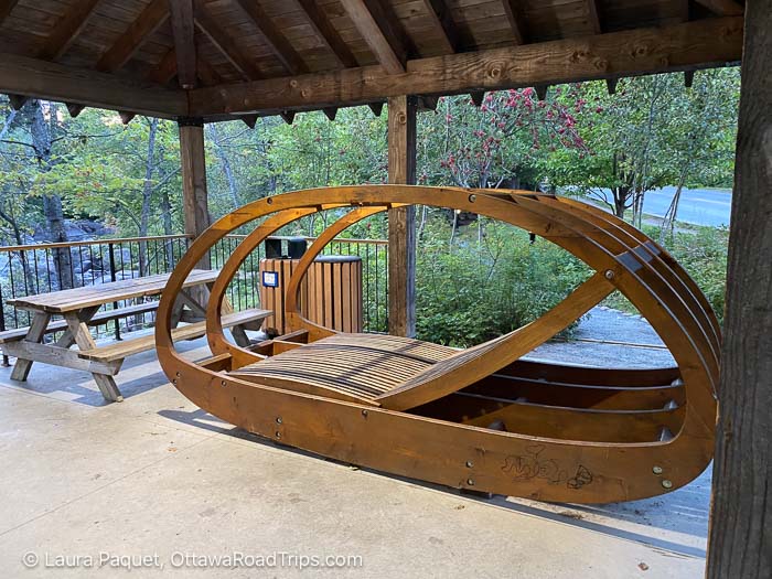wooden lounge chair and picnic table beside a river